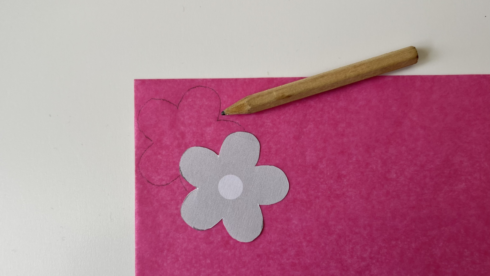 Blumenschablone liegt auf Transparentpapier, Schablone wird auf das Papier mit Bleistift übertragen